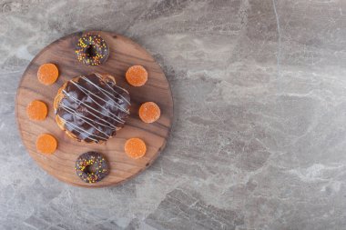 Marmelat, küçük çörekler ve mermer zemin üzerinde tahta bir tahta üzerinde çikolata kaplı pasta. Yüksek kalite fotoğraf