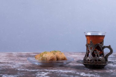 Mavi arka planda cam tabakta Türk Pakhlava 'sı olan bir bardak çay. Yüksek kalite fotoğraf