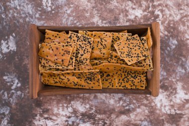 Ortadaki ahşap tepside siyah kimyonlu krakerler. Yüksek kalite fotoğraf