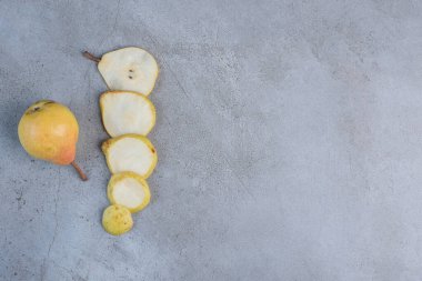 Armut dilimleri mermer arka planda koca bir armutun yanında dizilmiş. Yüksek kalite fotoğraf