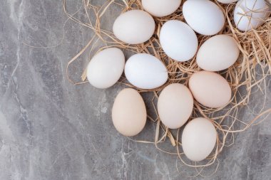 Mermer arka planda samanlı birkaç tane taze tavuk yumurtası. Yüksek kalite fotoğraf