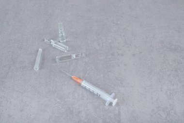 Gri arka planda tıbbi sıvı haplarla dolu boş bir şırınga. Yüksek kalite fotoğraf