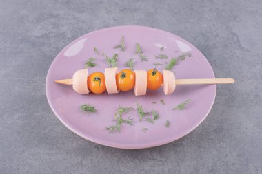 Vişne sarısı domatesli haşlanmış sosisli mor bir tabak. Yüksek kalite fotoğraf