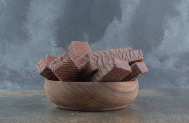 Çikolata kaplı gofretler ahşap arka planda küçük bir kasede yığılmış. Yüksek kalite fotoğraf