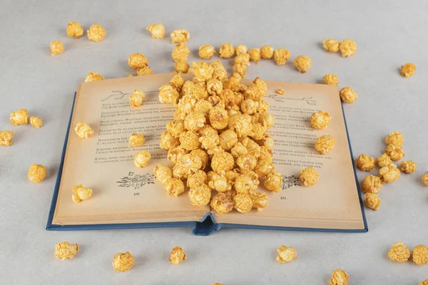 Open Book Heap Caramel Coated Popcorn Scattered All Marble Background — Stock Photo, Image