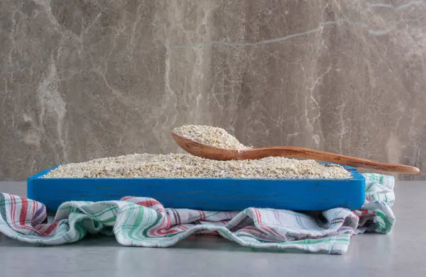 Short grain rice piled on a large tray on a towel on marble background. High quality photo