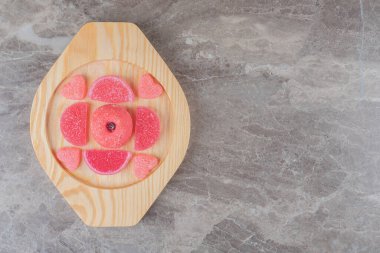 Küçük bir çöreğin etrafındaki marmelatlar mermer arka planda tahta bir tabakta. Yüksek kalite fotoğraf