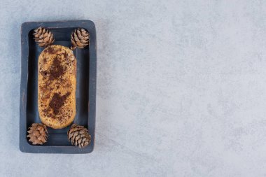 Mermer arka planda siyah tepside küçük pasta ve çam kozalakları. Yüksek kalite fotoğraf