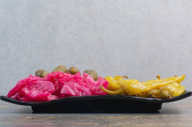 Bir tabak dolusu salatalık turşusu ve mermer zemin üzerinde kırmızı tuzlu lahana. Yüksek kalite fotoğraf