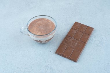 Mavi yüzeyde bir fincan sütlü kahve ve çikolata. Yüksek kalite fotoğraf