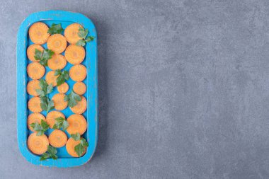 Tahta tepside mermer zemin üzerinde yeşiller ve dilimlenmiş havuç. Yüksek kalite fotoğraf