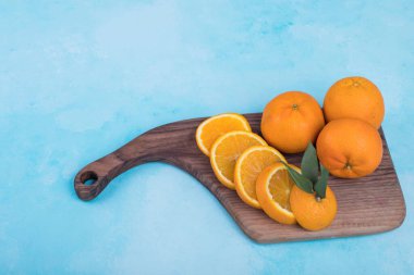 Mavi arka planda tahta bir tabakta dilimlenmiş sarı portakallar. Yüksek kalite fotoğraf