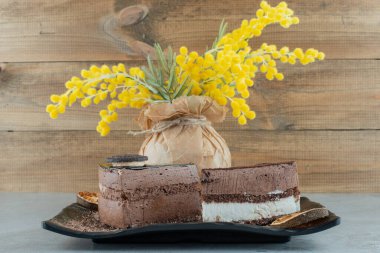 Çiçek vazosuyla siyah tabakta iki dilim kek. Yüksek kalite fotoğraf