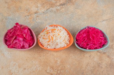 Mermer yüzeyde üç kase kırmızı ve beyaz lahana turşusu. Yüksek kalite fotoğraf