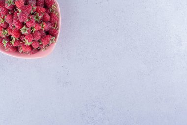 Mermer arka planda pembe bir kasede ahududu porsiyonu. Yüksek kalite fotoğraf