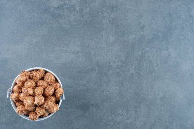 Kahverengi patlamış mısır şekeri mermer arka planda küçük bir kovaya doldurulmuş. Yüksek kalite fotoğraf