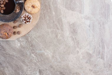 Bir fincan kahve, kurabiye, kahve çekirdeği ve mermer arka planda çam kozalağı. Yüksek kalite fotoğraf