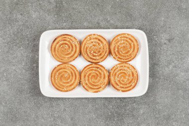 Beyaz kare tabakta susam tohumlu yuvarlak bisküviler. Yüksek kalite fotoğraf