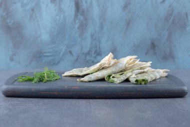 Tahtaya otlar ve dereotlar konmuş krepler.