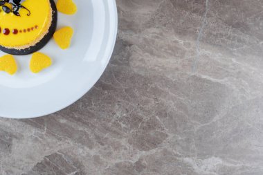 Küçük bir pastanın üzerindeki limon aromalı kaplama mermer zemin üzerinde marmelatlarla çevrili. Yüksek kalite fotoğraf