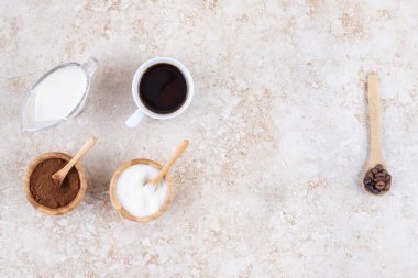 Bir fincan kahve, süt, şeker, kahve tozu ve kahve çekirdeği mermer arka planda. Yüksek kalite fotoğraf