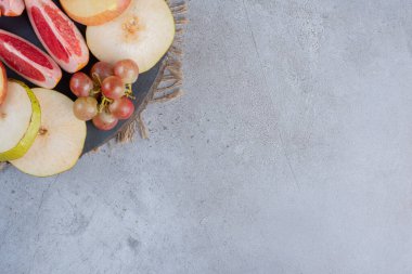 Armut ve greyfurt dilimleri, mermer zemin üzerinde tahta bir tahtanın üzerinde küçük bir üzüm kümesi. Yüksek kalite fotoğraf