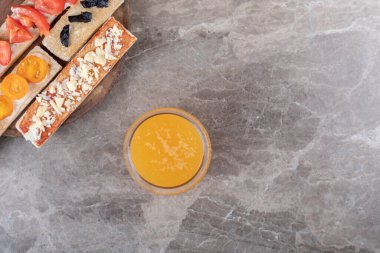 Tahtada portakal suyunun yanında, mermer zemin üzerinde dilimlenmiş meyve. Yüksek kalite fotoğraf