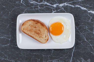 Tabakta, mermer zeminde kızarmış yumurtanın yanında tost. Yüksek kalite fotoğraf