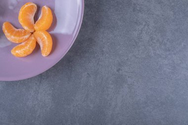 Mor tabakta taze mandalina dilimlerinin üst görüntüsü. Yüksek kalite fotoğraf