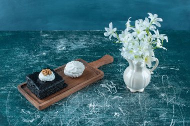 Çikolatalı pasta, kurabiye ve mavi arka planda bir vazo beyaz zambak. Yüksek kalite fotoğraf