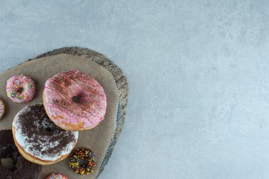 Mermer zemin üzerinde ahşap bir tahtanın üzerinde donut çeşitleri. Yüksek kalite fotoğraf