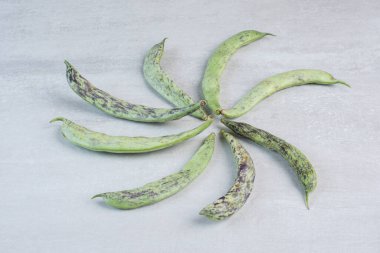 Gri yüzeye bir sürü yeşil fasulye konmuş. Yüksek kalite fotoğraf