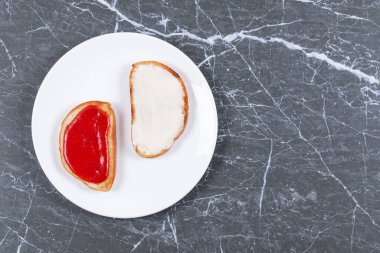 Tabakta, mermer zemin üzerinde iki dilim ekmek üzerinde nefis peynir ve kavanoz. Yüksek kalite fotoğraf