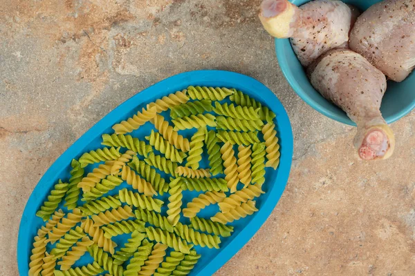 Onvoorbereide Spiraalvormige Macaroni Met Kippenpoten Blauwe Plaat Hoge Kwaliteit Foto — Stockfoto