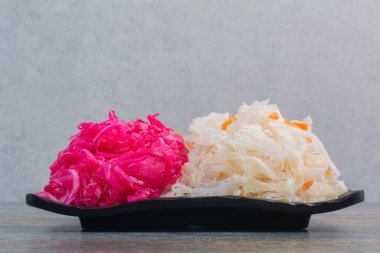 Mermer arka planda kırmızı tuzlu lahana dolu siyah bir tabak. Yüksek kalite fotoğraf