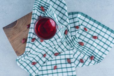 Dağılmış gül kalçaları ve mermer arka plandaki tahta kutunun üzerindeki havluya bir fincan çay. Yüksek kalite fotoğraf