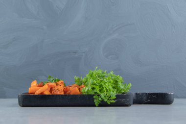 Maydanozun yanında dilimlenmiş balkabağı, tepside, mermer zemin üzerinde. Yüksek kalite fotoğraf