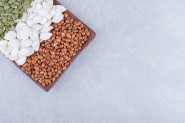 Çeşitli kırmızı fasulye tabakları, beyaz kabak tohumları ve mermer arka planda bezelyeler. Yüksek kalite fotoğraf