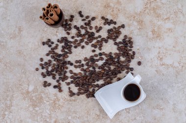 Ahşap bir fincanda tarçın parçalanmış kahve çekirdekleri ve mermer arka planda bir fincan kahvenin yanında duruyor. Yüksek kalite fotoğraf