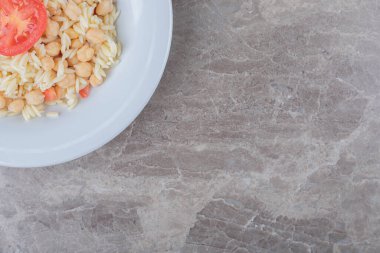 Nohut ve makarna, tabakta dilimlenmiş domates, mermer zemin. Yüksek kalite fotoğraf