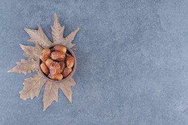 Yaprağın üzerinde, mermer arka plandaki kasede meyve var. Yüksek kalite fotoğraf
