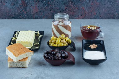 Krema, bal, çikolata, ekmek, peynir, siyah ve yeşil zeytin ve mermer zemin üzerinde bir fincan çay. Yüksek kalite fotoğraf