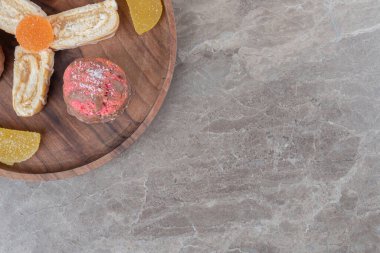 Pasta dilimleri, marmelatlar ve mermer arka plandaki ahşap tepside küçük bir pasta. Yüksek kalite fotoğraf