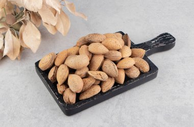 Yaprakların yanında mermer zemin üzerinde bir tepsi badem. Yüksek kalite fotoğraf