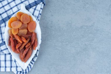 Lezzetli iki çeşit kurutulmuş meyve, kâsede, havlunun üstünde, mermer zemin üzerinde. Yüksek kalite fotoğraf