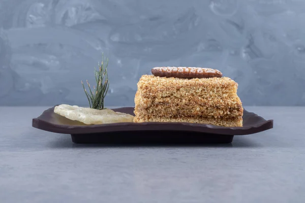 Stacked cake slices and a dried pineapple slice on a platter on marble background. High quality photo