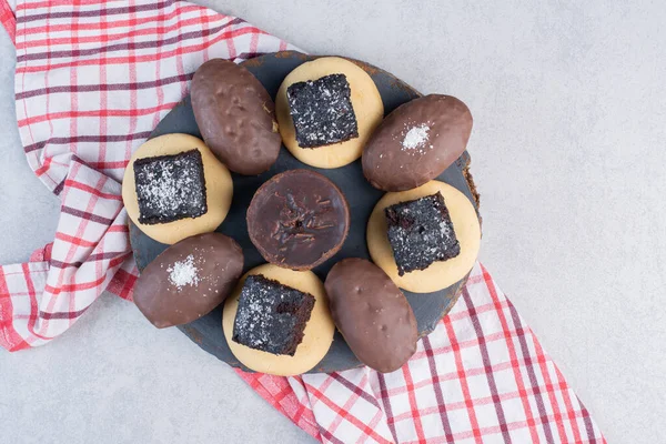 Chocolate cakes and cookies on a wooden board on marble background. High quality photo