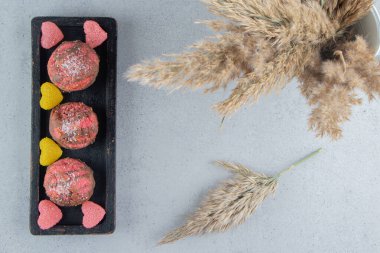 Bir tepsi kurabiye ve mermer arkaplandaki marmelatların yanında bir demet tüy otu sapı. Yüksek kalite fotoğraf