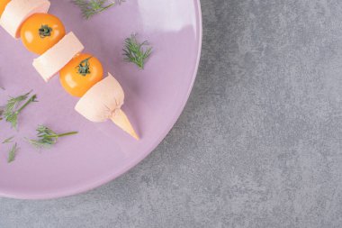 Vişne sarısı domatesli haşlanmış sosisli mor bir tabak. Yüksek kalite fotoğraf