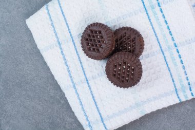 Masa örtüsünün üzerinde üç çikolatalı kurabiye var. Yüksek kalite fotoğraf